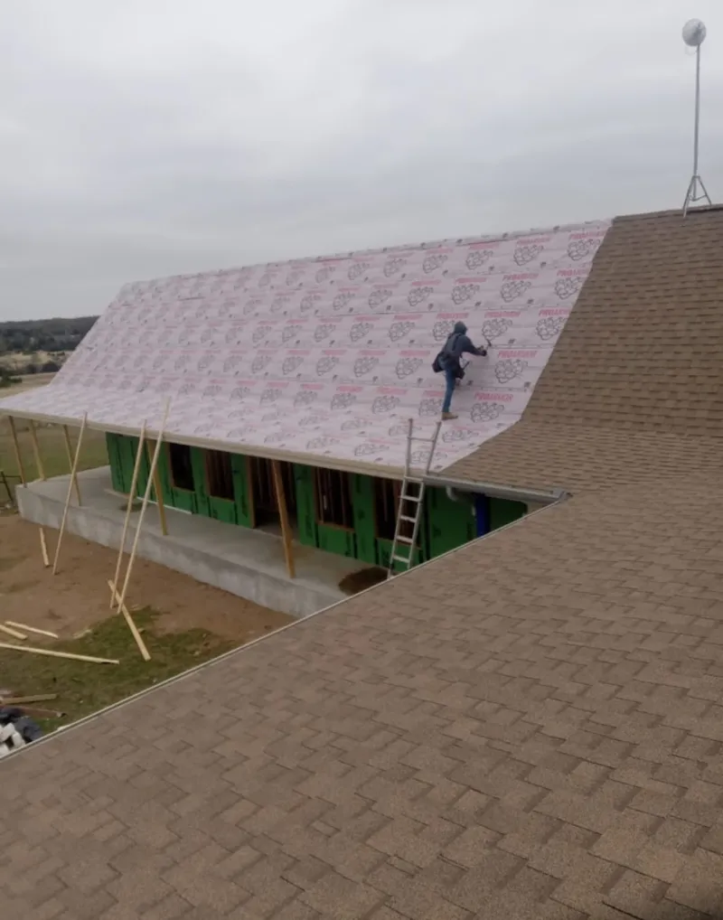 Worker preparing underlayment for a metal roof installation in Glocester